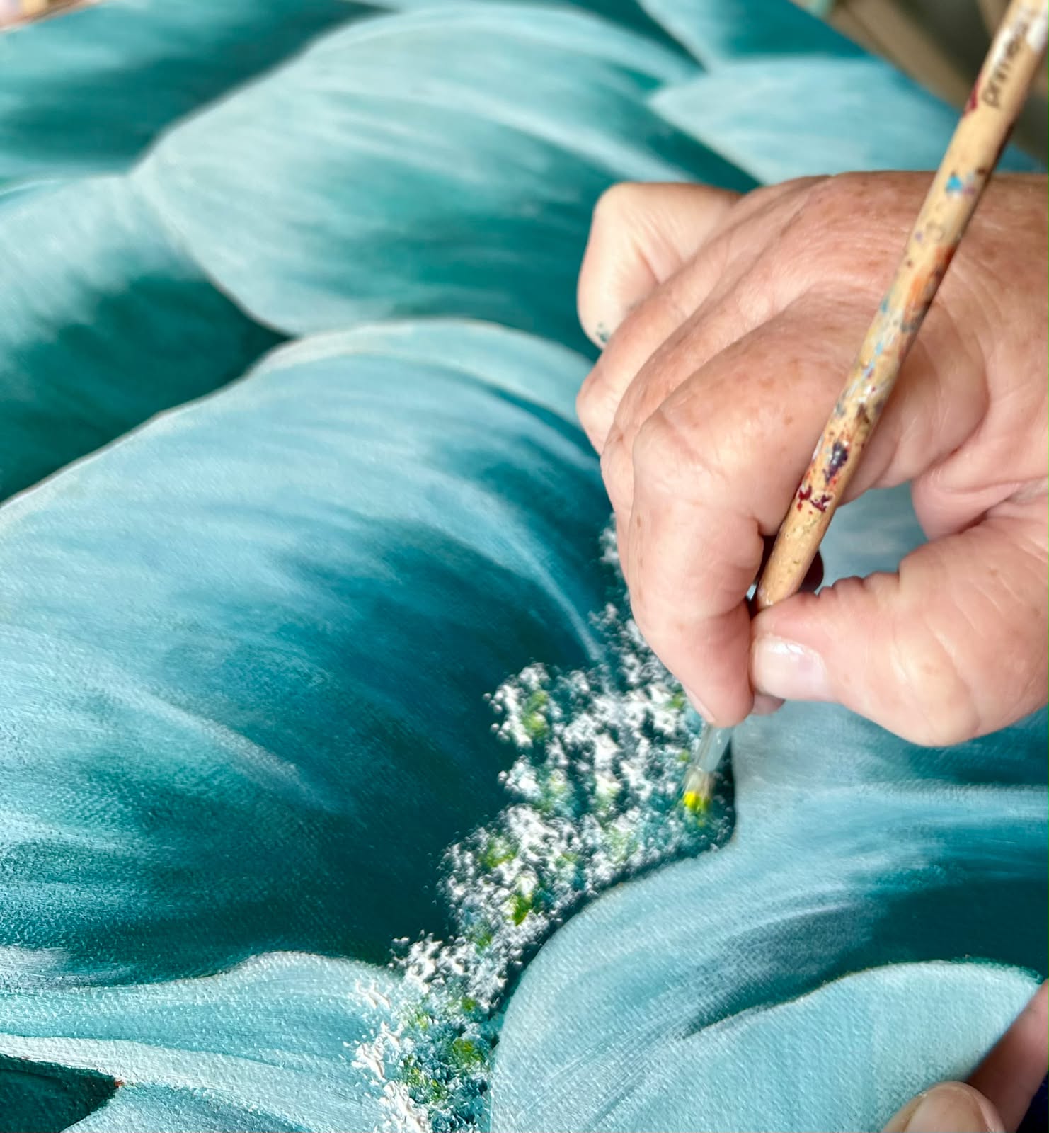 Close-up of brush detailing on a turquoise floral painting