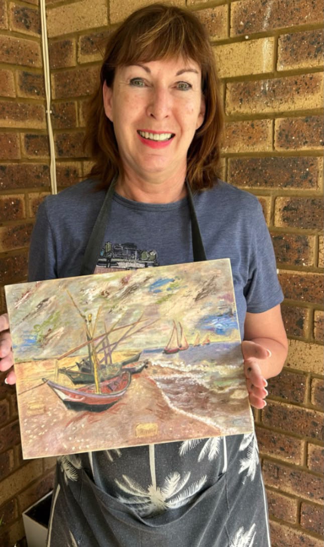 Smiling student holding her impressionist boats on the beach painting
