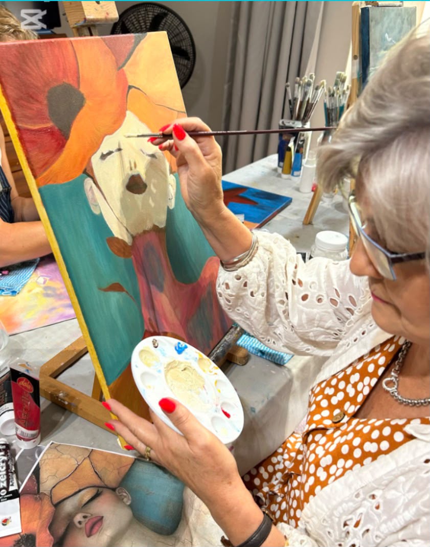 Student carefully painting a portrait with bold orange poppy florals